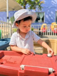 Preschool student exploring the water table outdoors